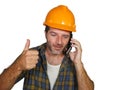 Happy efficient and cheerful workman or contractor man wearing builder hat tallking with satisfied customer on mobile phone