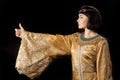 Happy Egyptian woman like Cleopatra with thumbs up gesture, on black background Royalty Free Stock Photo