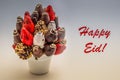 Happy Eid greeting card with red lettering; A bundle of edible flowers, arrangement of strawberries covered with chocolate