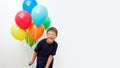 Happy eight year old boy with an armful of bright colorfull balloons celebrates birthday