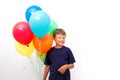Happy eight year old boy with an armful of bright colorfull balloons celebrates birthday