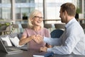 Happy elder businesswoman giving handshake to younger business partner man Royalty Free Stock Photo
