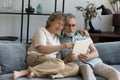 Happy elder family couple with digital device relaxing on sofa Royalty Free Stock Photo