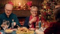 Happy elder woman clinking glasses with young person while enjoying Christmas dinner in family Royalty Free Stock Photo