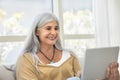 Happy elder woman using tablet for online communication at home Royalty Free Stock Photo