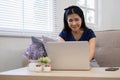 Happy elderly Asian woman in her 60s enjoys using social media on her laptop while relaxing in the living room. Royalty Free Stock Photo