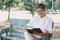 Happy elderly asian woman while sitting reading  book on the bench in the park. Concept of a happy lifestyle in the retirement Royalty Free Stock Photo