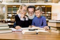 Happy elderly bearded man, grandfather and his cute grandson and granddaughter are sitting at the table in vintage old