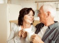 Happy elderly couple drinking coffee in the kitchen while sitting at the table. Royalty Free Stock Photo