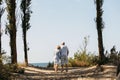 Happy elderly couple hold hands, stand among the trees, look at the sea Royalty Free Stock Photo