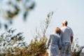 Happy elderly couple hold hands, stand among the trees, look at the sea Royalty Free Stock Photo