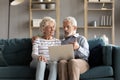 Happy elderly couple relax on couch using laptop Royalty Free Stock Photo