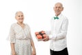 Happy elderly couple, senior man in white shirt present gift box to his old woman in white dress, celebrating birthday Royalty Free Stock Photo