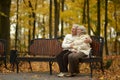Happy elderly couple sitting on bench in autumn park Royalty Free Stock Photo