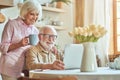 Happy elderly couple using laptop while spending morning together at the kitchen Royalty Free Stock Photo