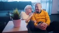 Happy elderly couple watching movies while sitting on the floor. Love and affection at old age Royalty Free Stock Photo