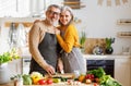 Happy elderly family couple wife and husband embracing while cooking vegetarian food together