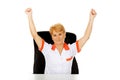 Happy elderly female doctor or nurse sitting behind the desk withd hands up Royalty Free Stock Photo