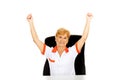 Happy elderly female doctor or nurse sitting behind the desk withd hands up Royalty Free Stock Photo