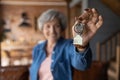 Happy elderly female homeowner pose in country cottage hold keys