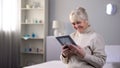 Happy elderly lady sitting alone and looking at photo, pleasant family memories