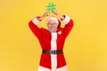 Happy elderly man with gray beard wearing santa claus costume holding green hashtag over his head, looking at camera with smile, Royalty Free Stock Photo