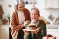 Happy elderly man in party hat holding chocolate cake with lit candles during Birthday celebration Royalty Free Stock Photo