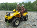 Happy elderly man and woman in camouflage suits and motorcycle helmets ride a yellow ATV. Sports, recreation Royalty Free Stock Photo