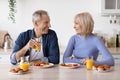 Happy elderly man and woman having breakfast at home, chatting Royalty Free Stock Photo