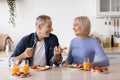 Happy elderly man and woman having lunch at home, chatting Royalty Free Stock Photo