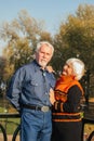 Happy elderly man and woman sitting on a bench in autumn day. Relaxed senior couple sitting on a park bench. Grandfather gently Royalty Free Stock Photo