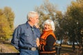 Happy elderly man and woman sitting on a bench in autumn day. Relaxed senior couple sitting on a park bench. Grandfather gently Royalty Free Stock Photo