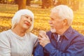 Happy elderly man and woman sitting on a bench in autumn day. Relaxed senior couple sitting on a park bench. Grandfather gently Royalty Free Stock Photo