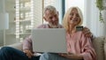 Happy elderly married couple man woman customers hugging making purchase online using laptop talking at home together