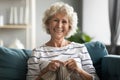 Smiling middle aged woman knitting warm sweater with woolen threads.