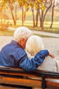 Happy elderly man and woman sitting on a bench in autumn day. Relaxed senior couple sitting on a park bench. Grandfather gently Royalty Free Stock Photo