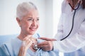 Happy Elderly patient talk with woman doctor at room in hospital. Doctor use stethoscope listening lung of elderly patient.