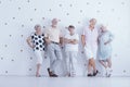 Happy elderly people in casual clothes in white studio with gold