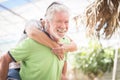 Happy elderly retired lifestyle people with caucasian couple smile and have fun together in piggyback walking outdoor - cheerful
