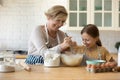 Happy grandmother and little granddaughter baking pies