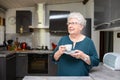 Happy elderly senior active woman drinking coffee in a modern kitchen at home