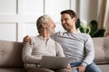 Happy elderly man holding computer enjoying fun time with son. Royalty Free Stock Photo