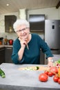 Happy elderly senior old active woman cooking at home in modern kitchen Royalty Free Stock Photo
