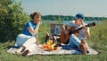 A happy elderly slender couple, a man and a woman, relax sitting on the grass with a guitar on a picnic on the river Royalty Free Stock Photo