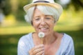 happy elderly woman senior blowing on dandelion Royalty Free Stock Photo