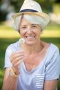 Happy elderly woman senior sitting on grass blowing on dandelion Royalty Free Stock Photo