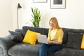 Happy elderly woman sit relax on couch in living room, work on laptop, smiling. Modern mature 60s female enjoy leisure Royalty Free Stock Photo