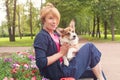 Happy elderly woman sitting with dog on bench in blossom summer park