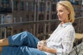 Happy elderly woman sitting on terrace with cup of coffee and enjoying beautiful sunny morning Royalty Free Stock Photo
