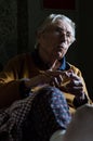 Happy elderly woman sittingin a dark room having conversation with her family. Royalty Free Stock Photo